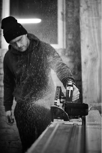 man working in a workshop with a circular saw